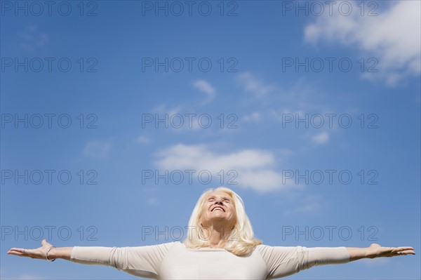 Upward view of senior woman with arms outstretched