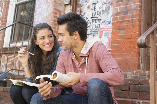 Young couple reading book and doing crossword