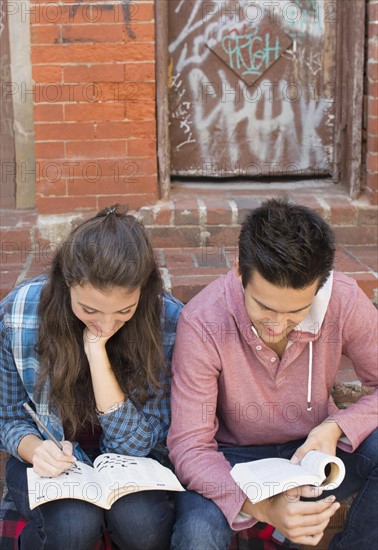 Young couple reading book and doing crossword