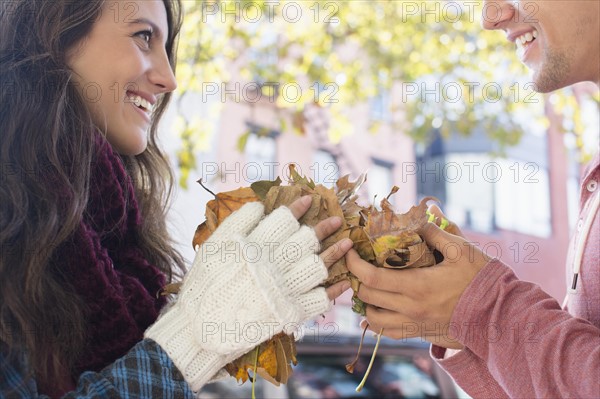 Young couple holding autumn leaves