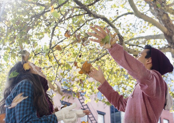 Young couple throwing autumn leaves