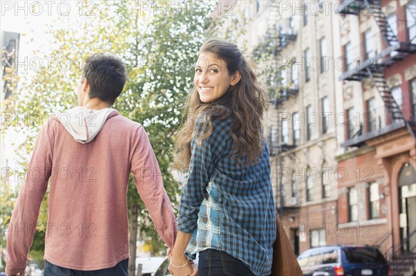 Young couple holding hands on sidewalk