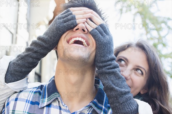 Young woman covering her boyfriend's eyes