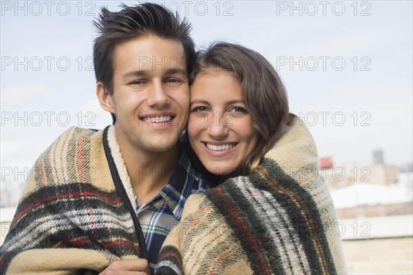 Portrait of young couple wrapped in blanket