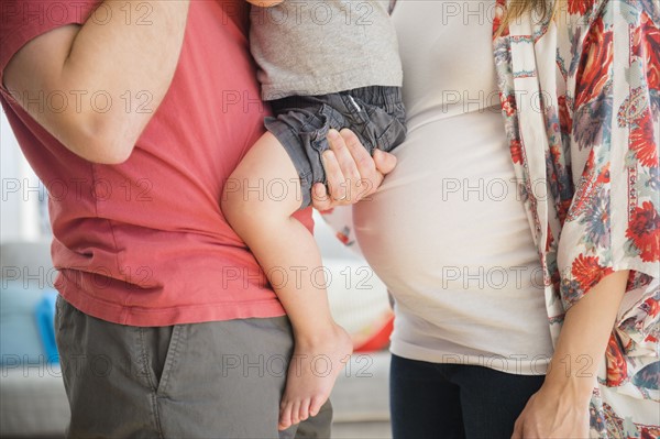 Mid-section of parents with son (2-3) in living room