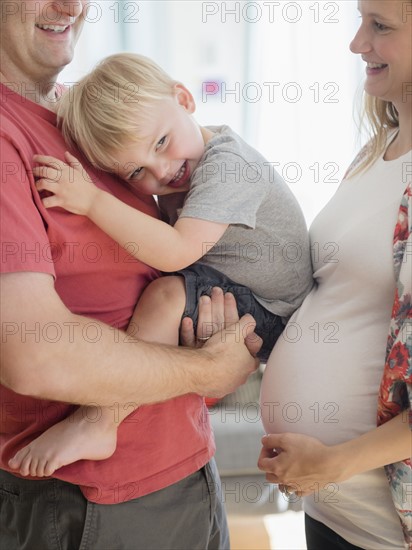 Happy boy (2-3) spending time with his parents in living room