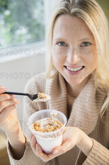 Portrait of woman eating yoghurt with cereals