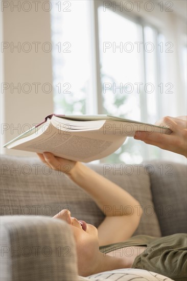 Woman reading book on sofa