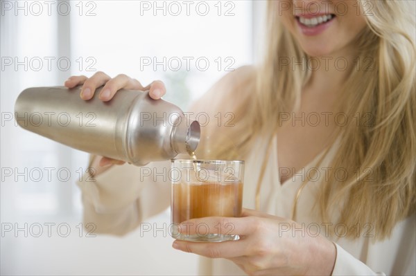 Woman pouring cocktail into glass