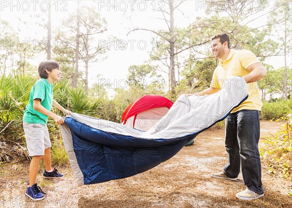 Father and son (12-13) preparing sleeping bag for camping