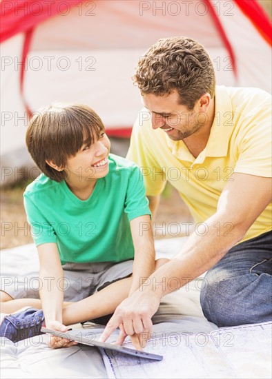 Father and son (12-13) using digital table at camping