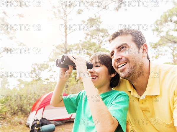 Father and son (12-13) using binoculars