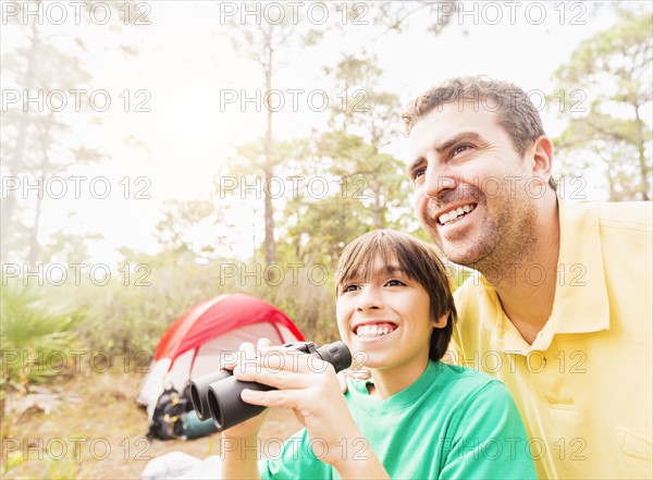 Father and son (12-13) using binoculars