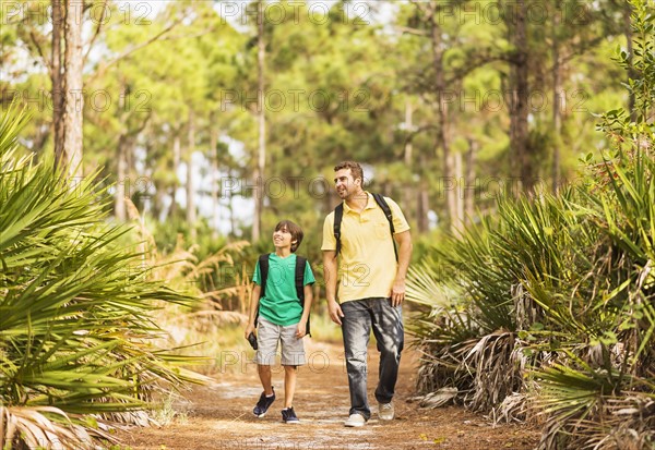 Father and son (12-13) walking through forest