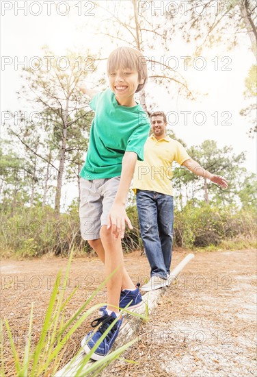 Father and son (12-13) balancing on log