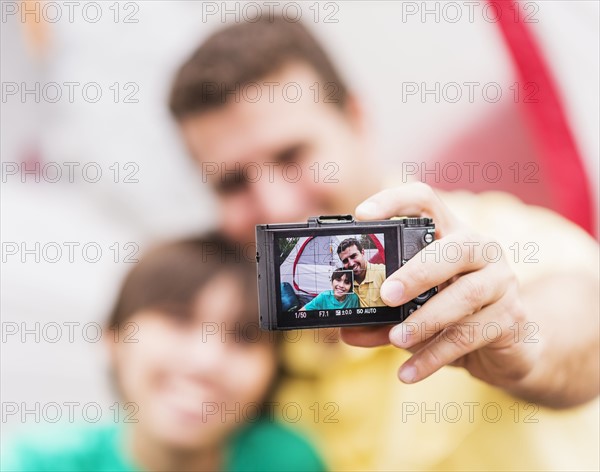 Father and son (12-13) taking selfie in front of tent