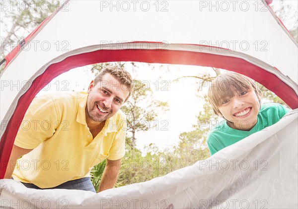 Portrait of father and son (12-13) looking into tent