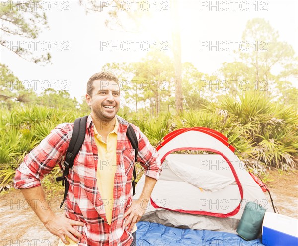 Man with backpack in front of tent