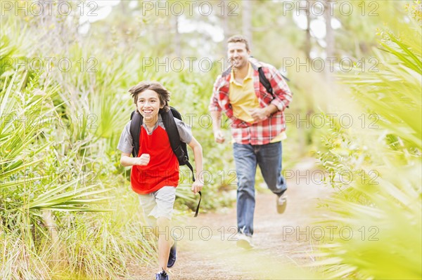 Father and son (12-13) running in forest