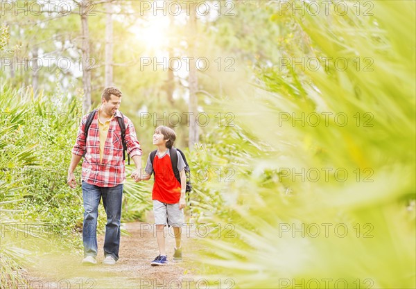 Father and son (12-13) walking in forest