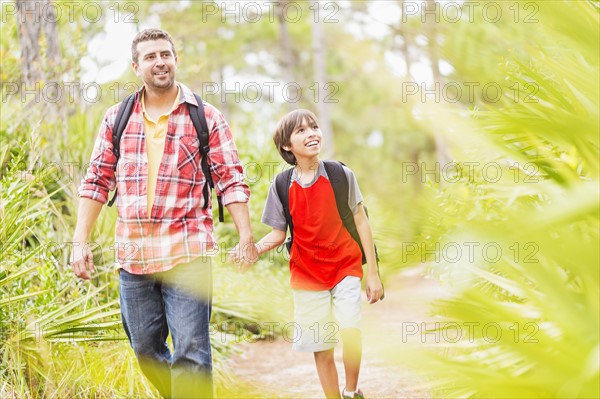 Father and son (12-13) walking in forest
