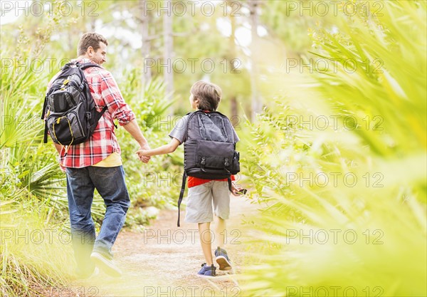 Father and son (12-13) walking in forest