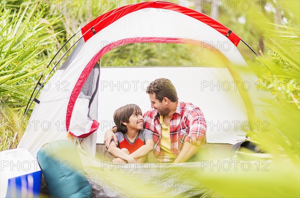 Father and son (12-13) sitting in tent