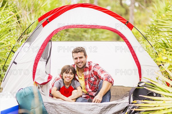 Father and son (12-13) sitting in tent