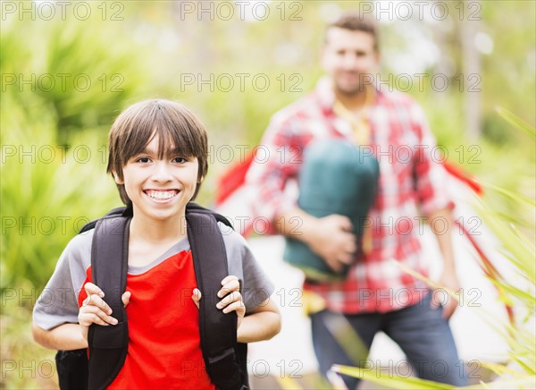 Portrait of boy (12-13) in forest with his father in background