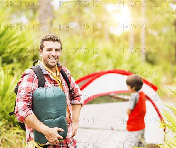 Portrait of man in forest with his son (12-13) in background