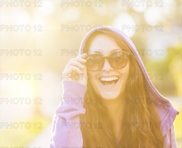 Portrait of smiling woman in hoodie with sunglasses