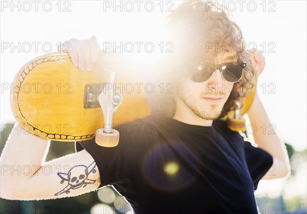 Man holding skateboard on his arms