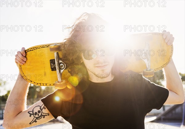 Man holding skateboard on his arms