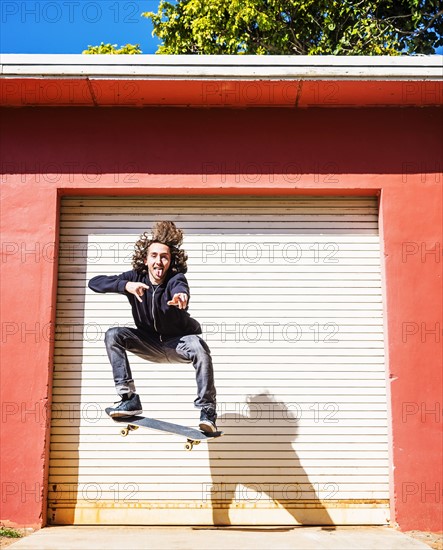 Man jumping on skateboard against closed garage door