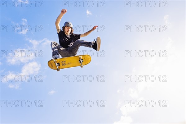 Man jumping on skateboard against sky and clouds