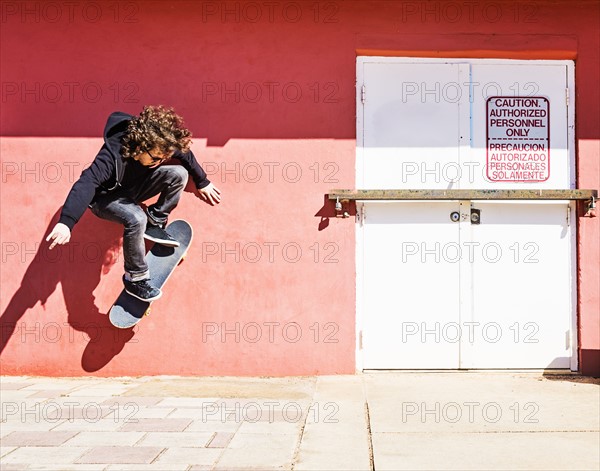 Man skating near red wall