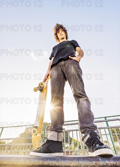 Man leaning on skateboard in skatepark