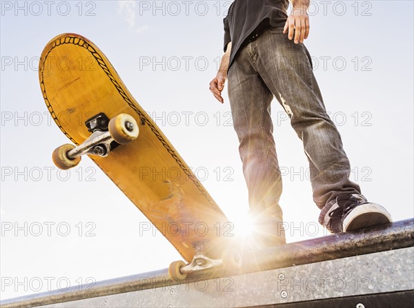 Man with skateboard at the edge of ramp