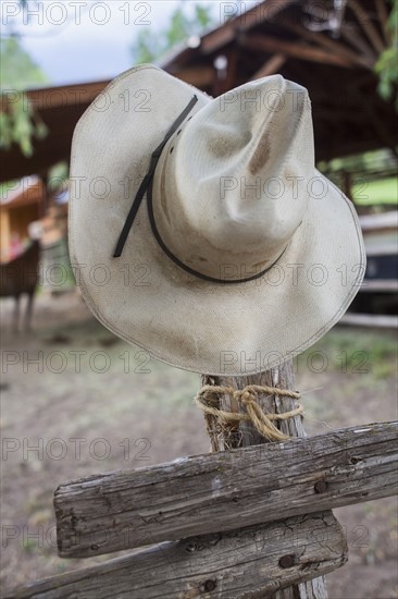 Cowboy hat hanging on wooden fence