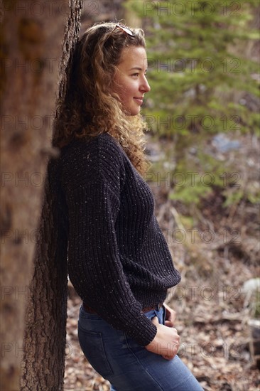 Portrait of young woman leaning on tree