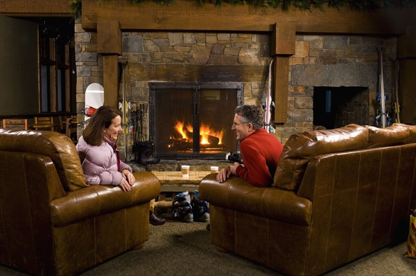 Man and woman chatting in front of fireplace