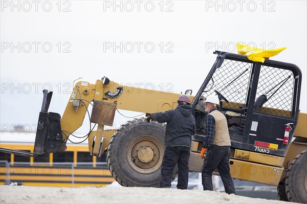 Two men standing next to earthmover