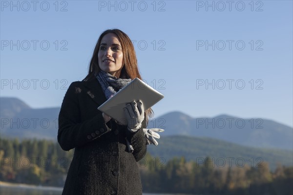 Woman with tablet by lake