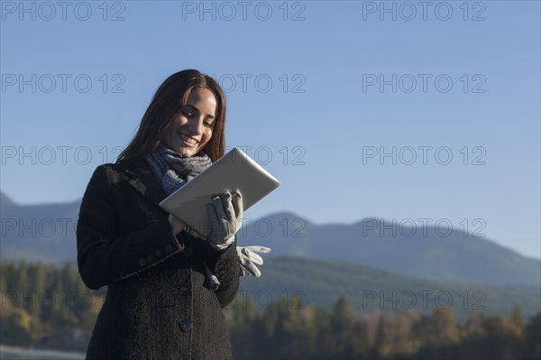 Woman with tablet by lake