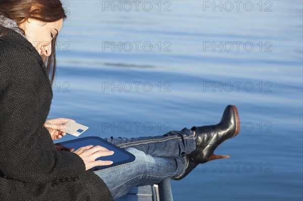 Woman with tablet by lake