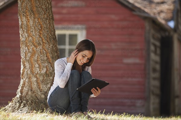 Woman with tablet sitting under tree