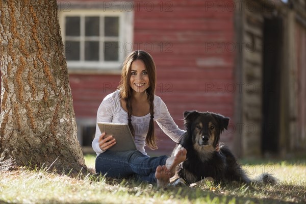 Woman sitting with dog under tree