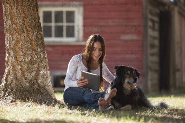 Woman sitting with dog under tree