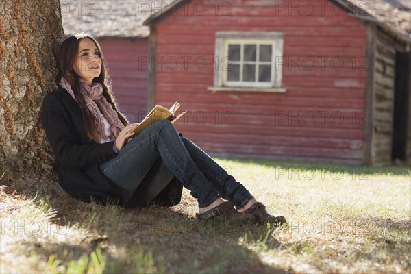 Woman with book sitting under tree