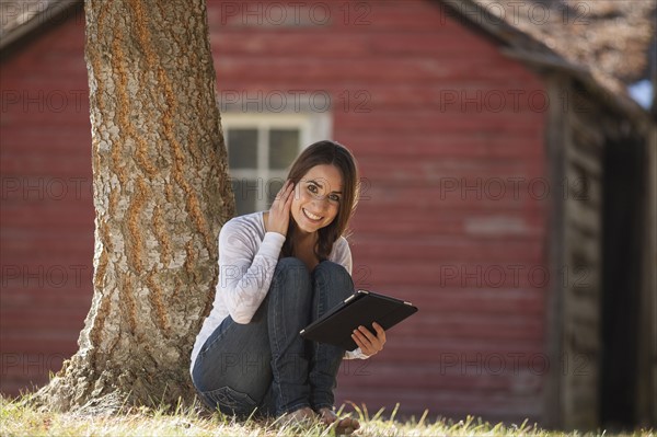 Portrait of woman sitting outdoors with tablet